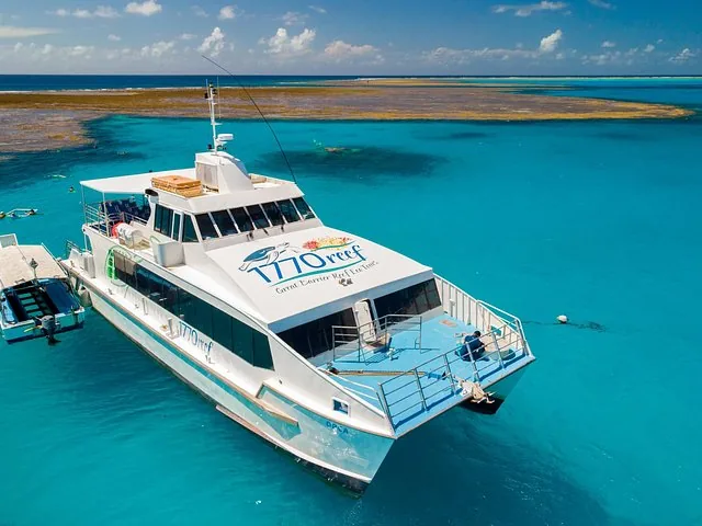Weißes Ausflugsboot vor Anker in leuchtend blauem Wasser nahe einem Korallenriff